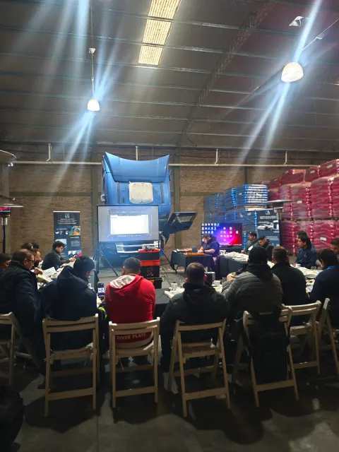 Participantes sentados durante el curso Scania en Buenos Aires, frente a un camión y pantallas de presentación