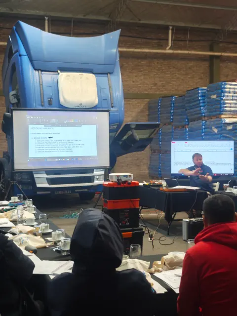 Presentación frente a un camión durante el curso Scania en Buenos Aires, con participantes y pantallas
