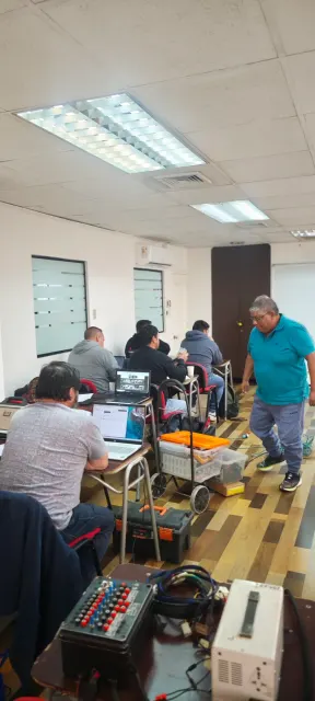 Participantes y bancos de trabajo en la capacitación de reparación de módulos electrónicos en Chile