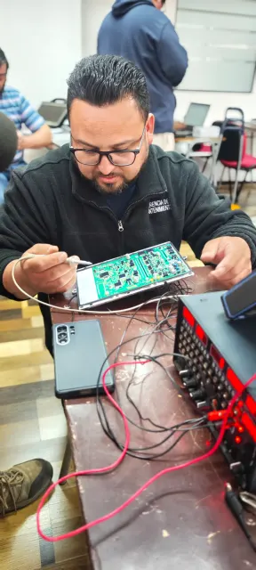 Participante realizando mediciones sobre una placa electrónica durante la práctica en Chile