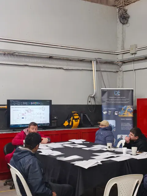 Participantes reunidos alrededor de una mesa con una pantalla y material de trabajo en la capacitación Sprinter Módulo 3 en Neuquén