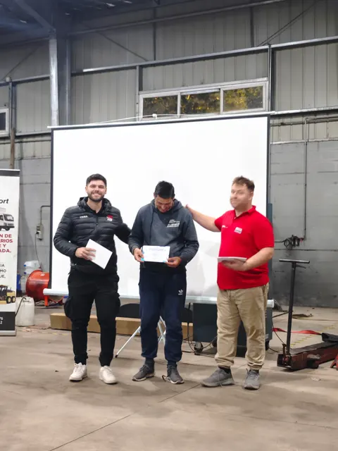 Participante con su certificado junto a los instructores del curso Volkswagen MAN D08